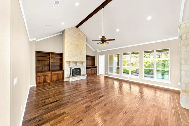 a view of an empty room with a fireplace and wooden floor