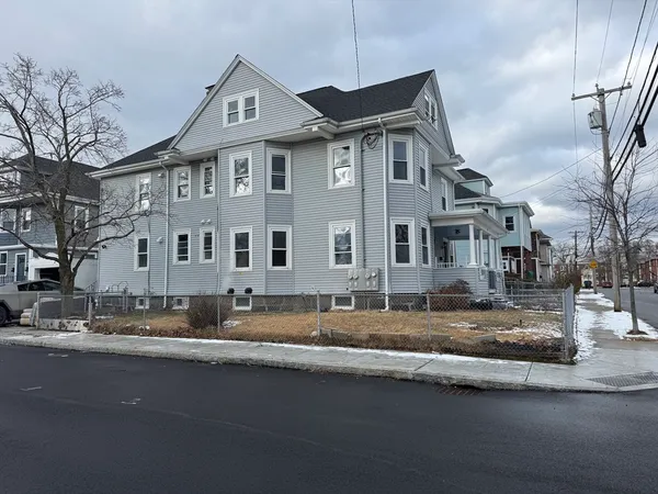 a front view of a house with a yard and large tree