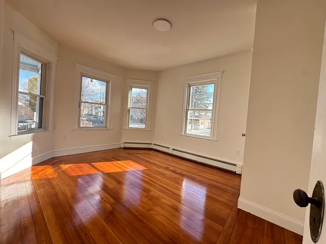 a view of empty room with window and wooden floor