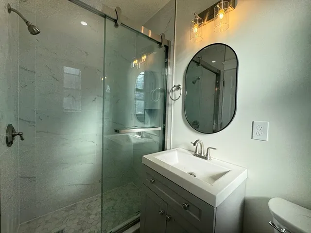 a bathroom with a sink shower and a mirror