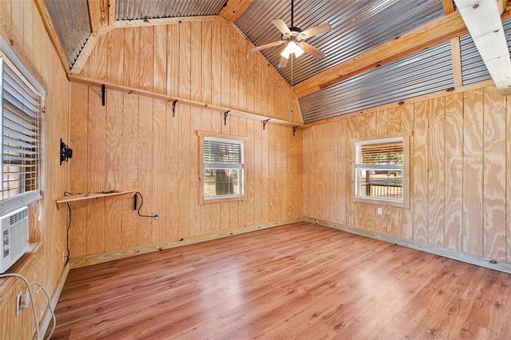 134 Maple Avenue Streetman, TX 75859 - Photo 13 of 19 Unfurnished room with light wood-style floors, wooden walls, plenty of natural light, ceiling fan, and beam ceiling