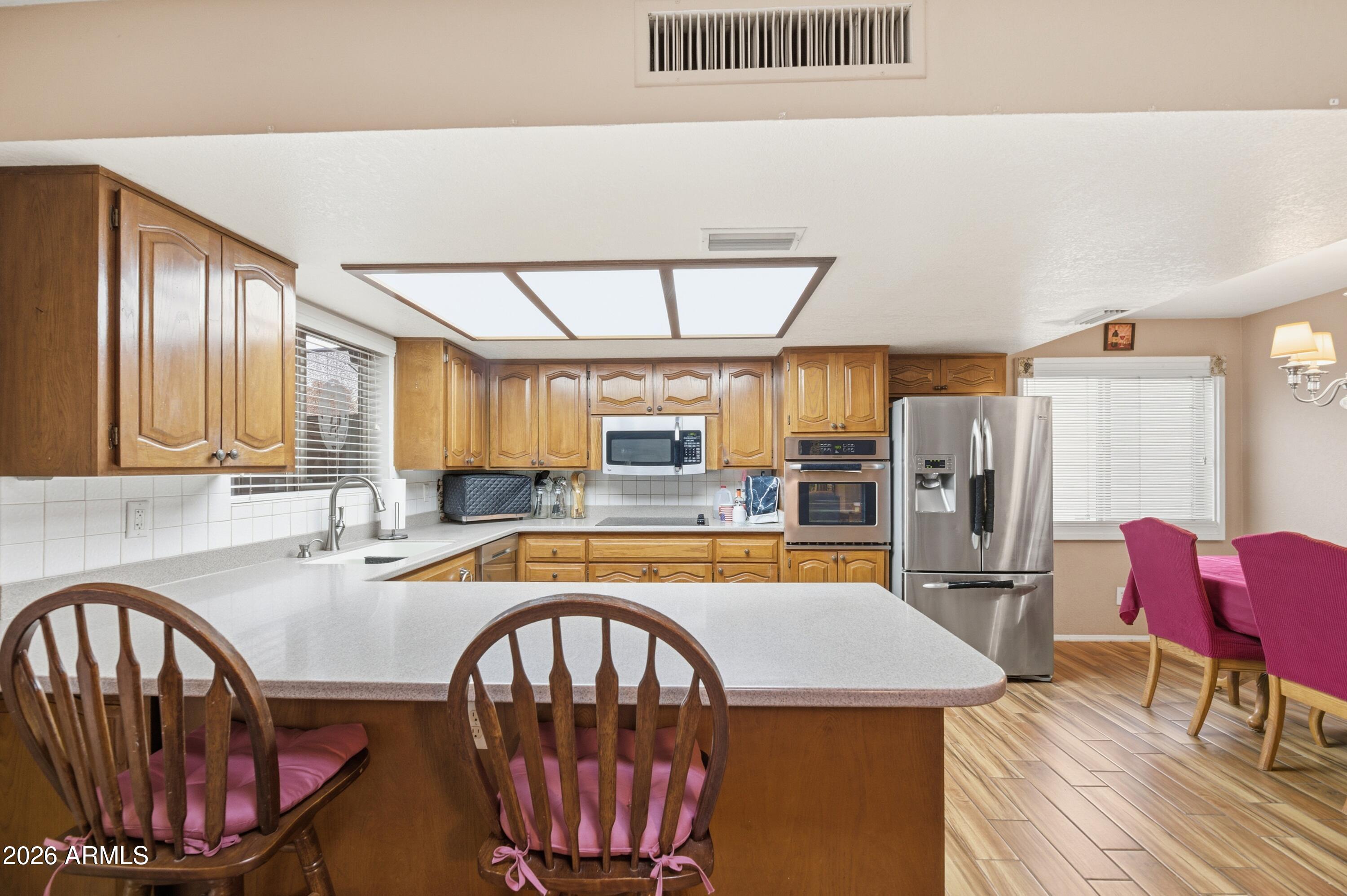 30 East Palo Verde Street Gilbert, AZ 85296 - Photo 7 of 38 a kitchen with stainless steel appliances granite countertop a stove a refrigerator a kitchen island a table and chairs
