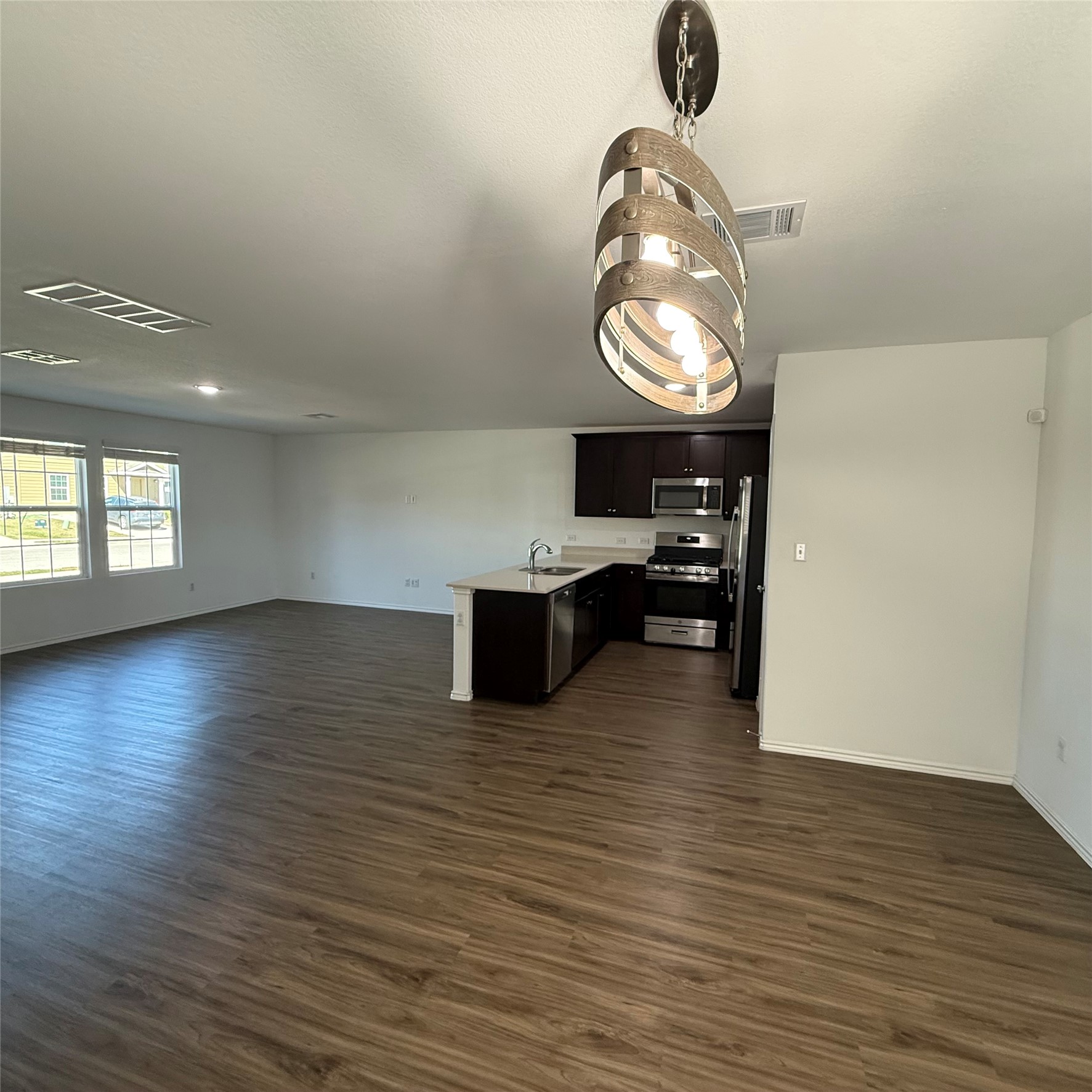 13711 Mussel Run Elgin, TX 78621 - Photo 28 of 31 Kitchen featuring open floor plan, light countertops, stainless steel appliances, a peninsula, and dark wood-style flooring
