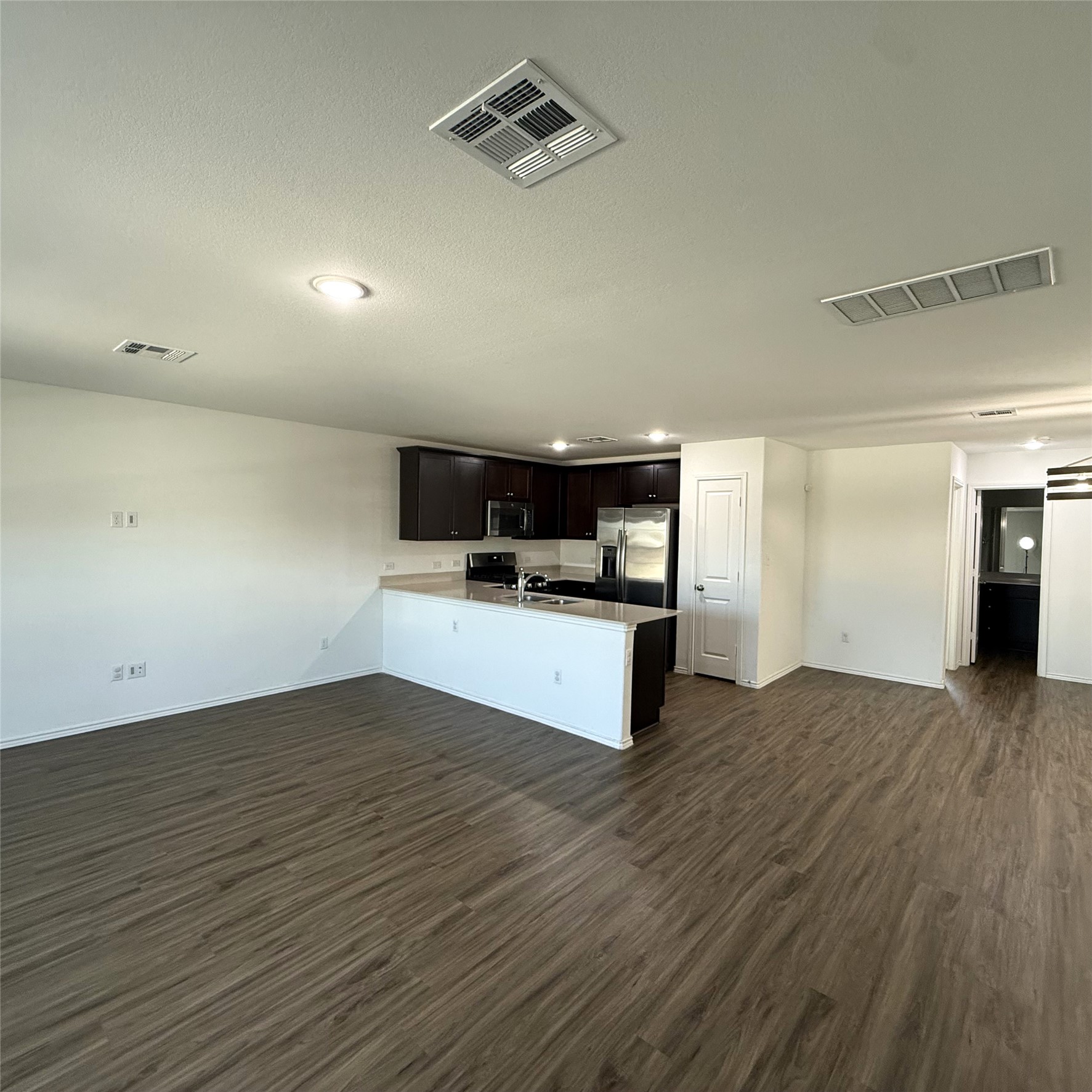 13711 Mussel Run Elgin, TX 78621 - Photo 29 of 31 Kitchen featuring open floor plan, a peninsula, light countertops, dark wood finished floors, and stainless steel appliances