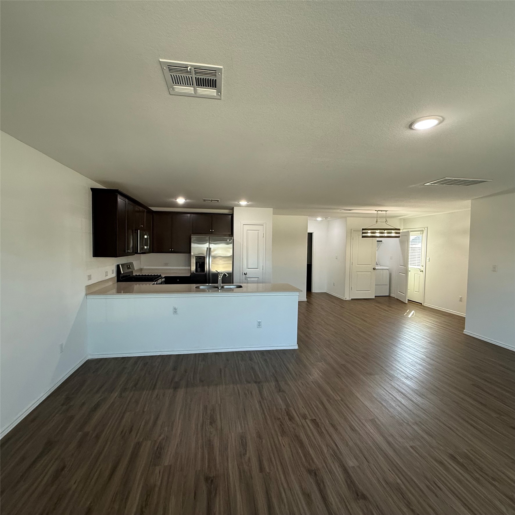 13711 Mussel Run Elgin, TX 78621 - Photo 30 of 31 Kitchen with light countertops, a peninsula, recessed lighting, open floor plan, and dark wood-type flooring