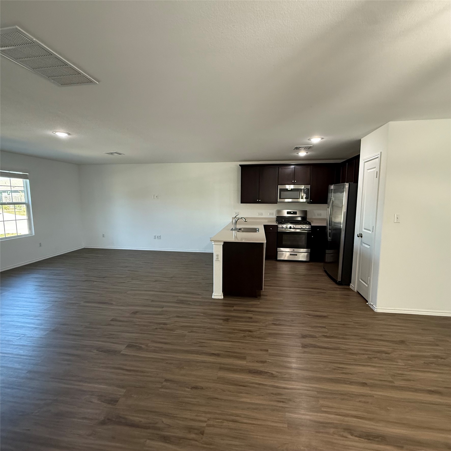 13711 Mussel Run Elgin, TX 78621 - Photo 31 of 31 Kitchen with open floor plan, dark wood finish cabinetry, stainless steel appliances, light countertops, and dark wood-style flooring