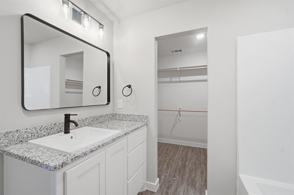 4209 Ranger Road Abilene, TX 79601 - Photo 7 of 10 Bathroom with vanity, a walk in closet, and dark wood-type flooring
