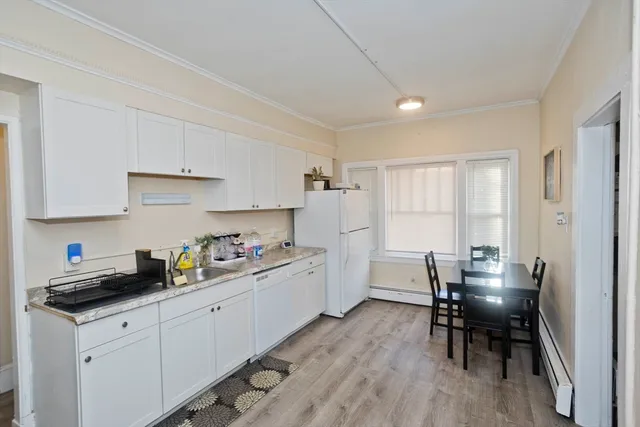 a kitchen with a dining table chairs and refrigerator