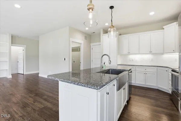 a kitchen with stainless steel appliances granite countertop a sink dishwasher and white cabinets with wooden floor
