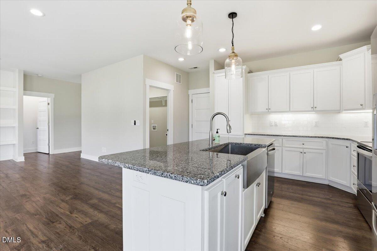 2249 Brogden Road Smithfield, NC 27577 - Photo 14 of 30 a kitchen with stainless steel appliances granite countertop a sink dishwasher and white cabinets with wooden floor