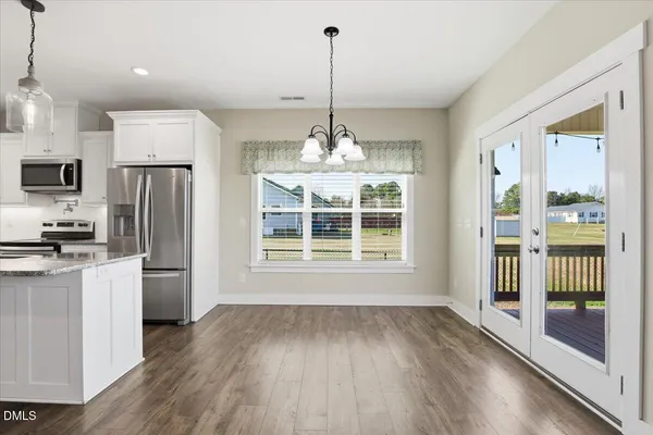 a view of a kitchen with stainless steel appliances granite countertop a refrigerator a oven a sink with a dining table and chairs