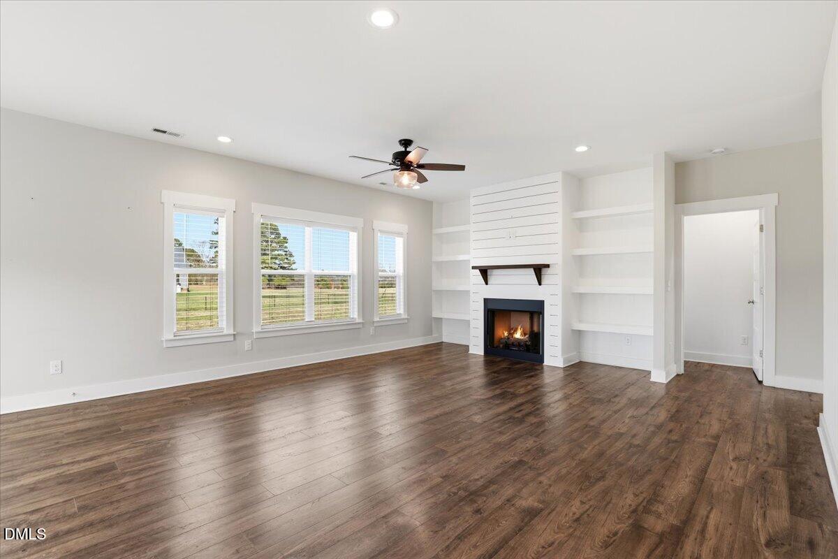 2249 Brogden Road Smithfield, NC 27577 - Photo 9 of 30 a view of an empty room with wooden floor fireplace and a window