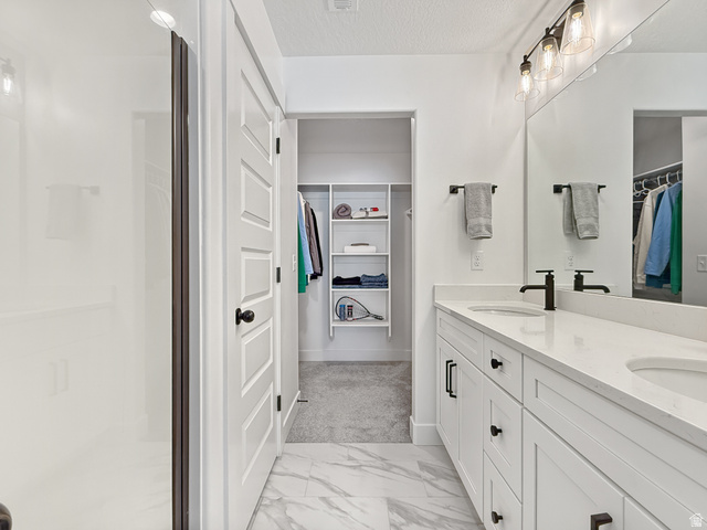 641 Desert Willow Drive Mapleton, UT 84664 - Photo 22 of 41 Full bathroom featuring a spacious closet, double vanity, light marble finish flooring, a textured ceiling, and a shower stall