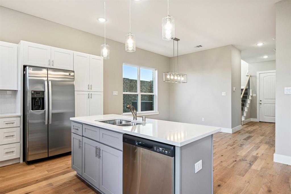 1711 Paytyn Drive Allen, TX 75013 - Photo 12 of 37 Kitchen with stainless steel appliances, a kitchen island with sink, pendant lighting, and white cabinets