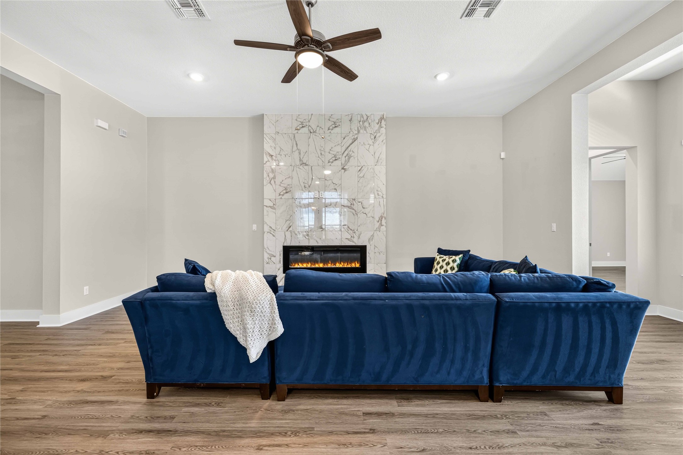 605 A Mallow Road Leander, TX 78641 - Photo 8 of 29 A spacious living area featuring a modern fireplace with a stunning tiled surround and sleek wood flooring.