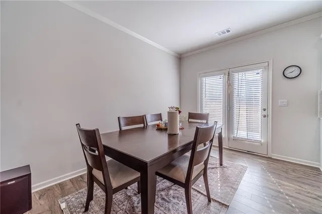 a kitchen with stainless steel appliances granite countertop a sink a stove a dining table and chairs with wooden floor