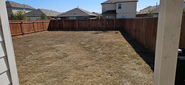 a view of backyard with wooden fence