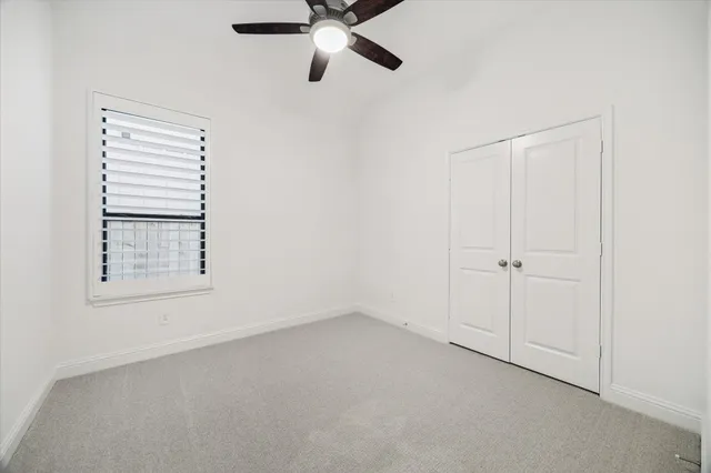 an empty room with a ceiling fan and window