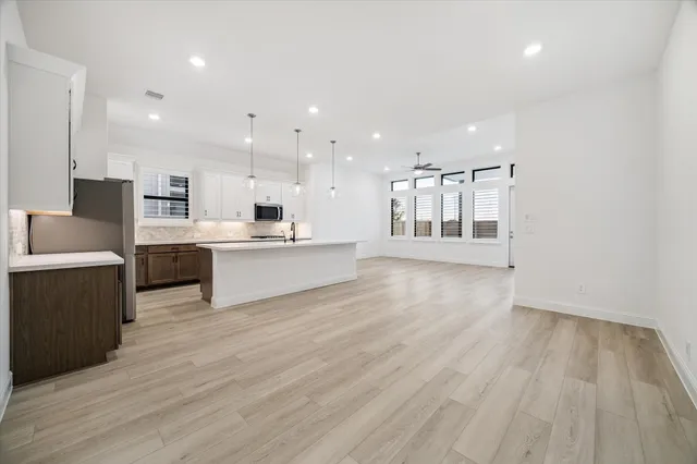 a large white kitchen with wooden floors and white stainless steel appliances