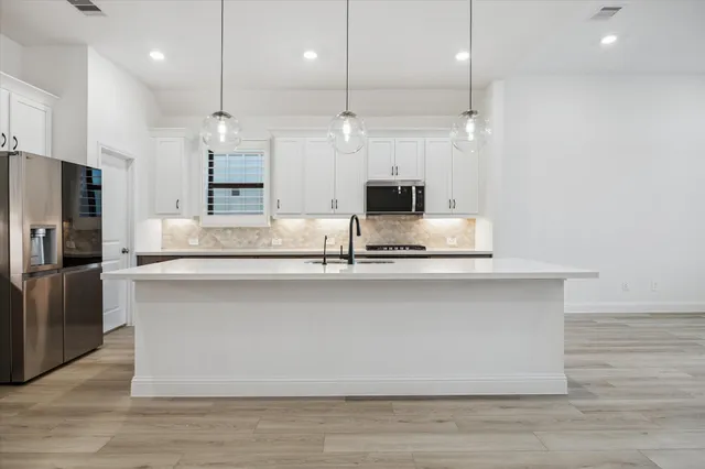 a large kitchen with kitchen island a large counter top stainless steel appliances and cabinets