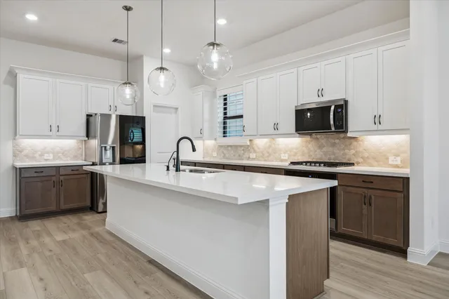 a kitchen with kitchen island granite countertop a sink cabinets and stainless steel appliances