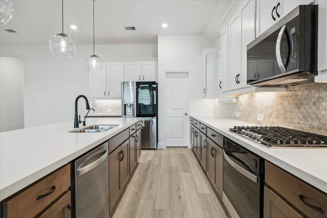 a kitchen with stainless steel appliances granite countertop a sink a stove and a wooden floors