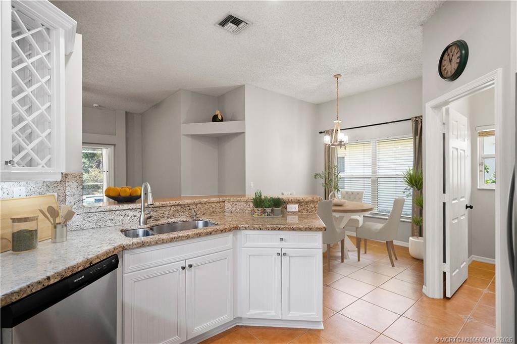 7221 Southeast Seagate Lane Stuart, FL 34997 - Photo 21 of 51 a very nice looking open kitchen with granite countertop a sink white cabinets a dining table and chairs