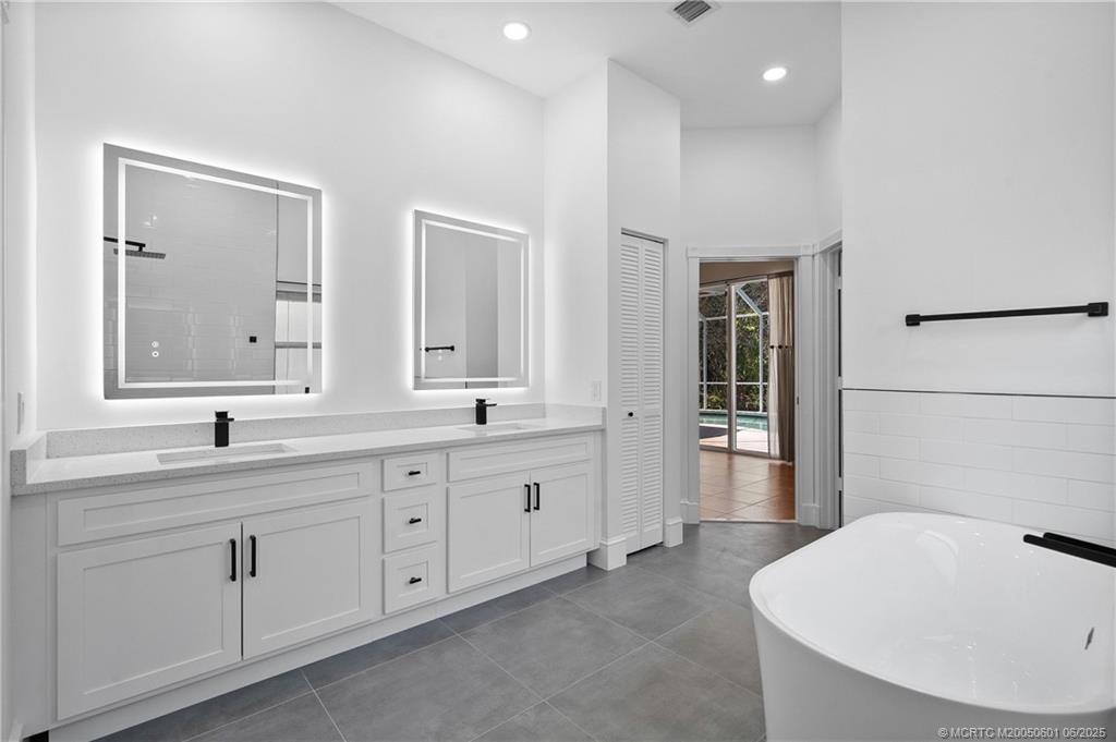 7221 Southeast Seagate Lane Stuart, FL 34997 - Photo 5 of 51 a bathroom with a tub a sink and mirror