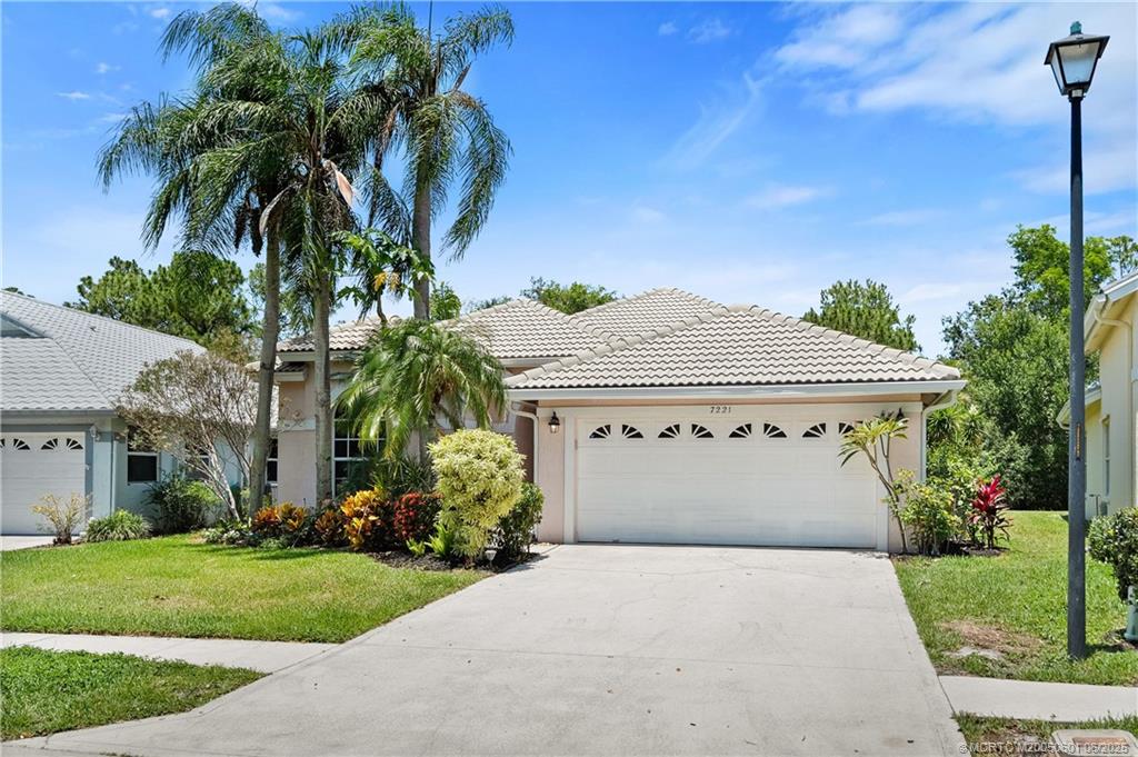7221 Southeast Seagate Lane Stuart, FL 34997 - Photo 8 of 51 a front view of a house with a yard and garage