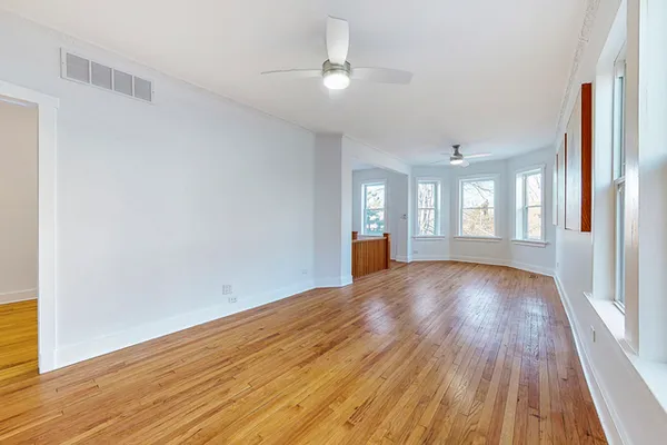 an empty room with wooden floor and windows