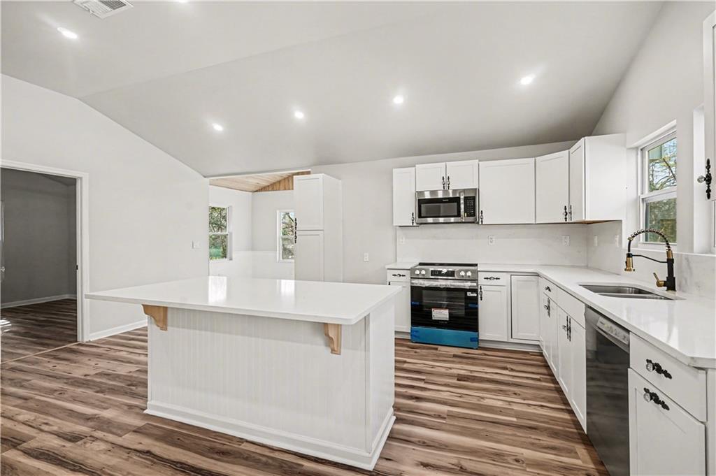 1004 Mapp Street Madison, GA 30650 - Photo 9 of 30 a kitchen with stainless steel appliances granite countertop a stove and white cabinets