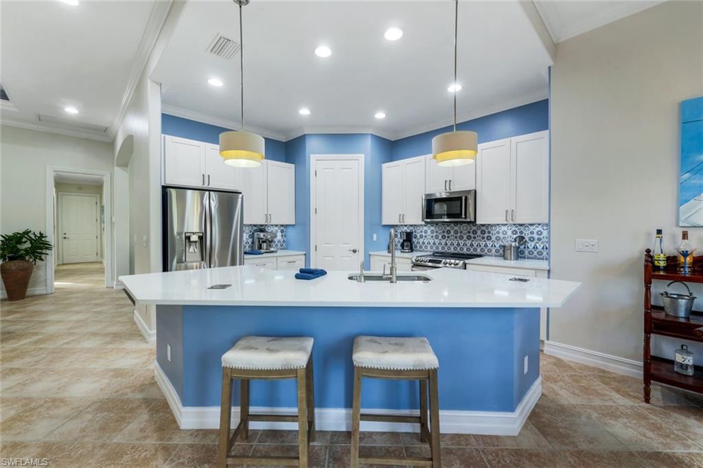 7688 Cottesmore Drive Naples, FL 34113 - Photo 13 of 45 a kitchen with cabinets and chairs