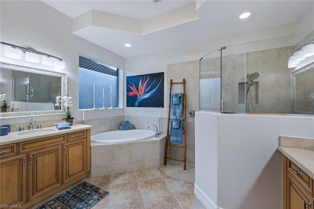 7688 Cottesmore Drive Naples, FL 34113 - Photo 23 of 45 a bathroom with a double vanity sink mirror and bathtub