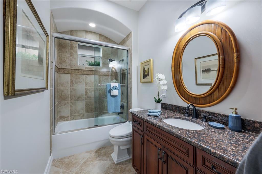 7688 Cottesmore Drive Naples, FL 34113 - Photo 25 of 45 a bathroom with a granite countertop toilet a sink and a mirror