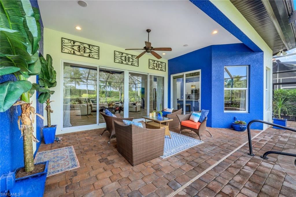 7688 Cottesmore Drive Naples, FL 34113 - Photo 32 of 45 a living room filled with furniture and floor to ceiling windows