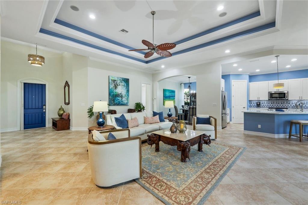 7688 Cottesmore Drive Naples, FL 34113 - Photo 7 of 45 a living room with furniture a chandelier and a rug