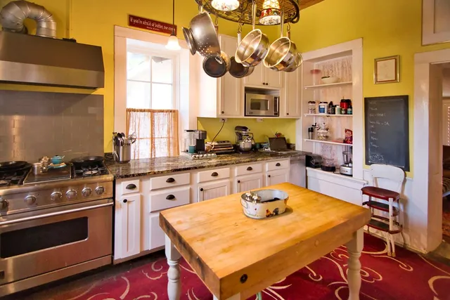 a kitchen with a stove a sink dishwasher and white cabinets with wooden floor