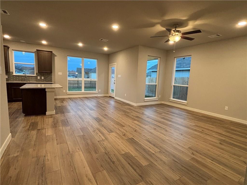 4229 Centerfire Road Waco, TX 76705 - Photo 4 of 14 an empty room with wooden floor and a kitchen