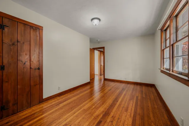 a view of an empty room with window and wooden floor