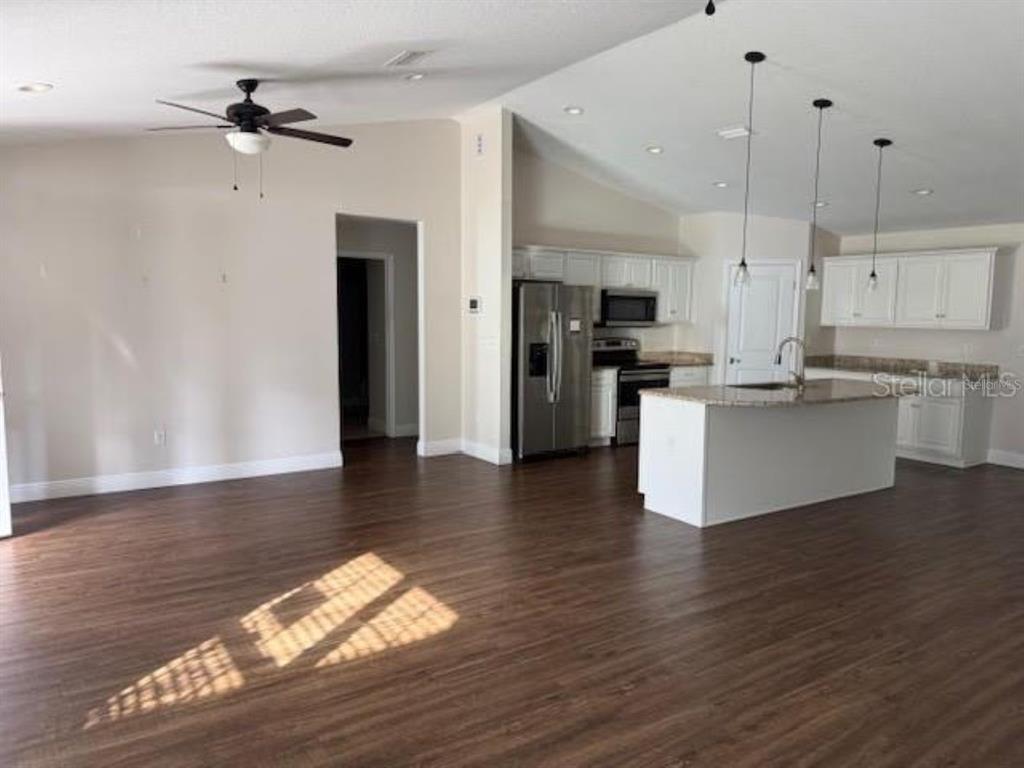 3707 Southeast 24th Street Ocala, FL 34471 - Photo 2 of 14 a open kitchen with stainless steel appliances granite countertop a stove top oven a refrigerator a sink and a dining table with wooden floor