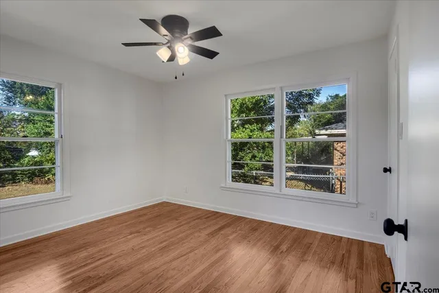 a view of an empty room with a window and wooden floor