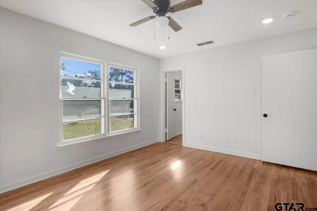 a view of an empty room with a window and wooden floor