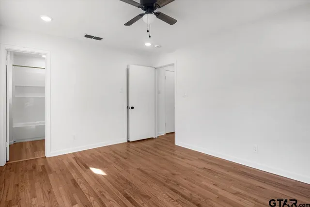 an empty room with wooden floor a ceiling fan and closet