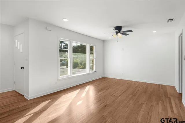 a view of an empty room with a window and wooden floor