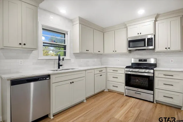 a kitchen with cabinets stainless steel appliances and wooden floor