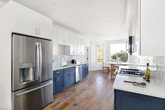 a kitchen with kitchen island white cabinets and stainless steel appliances