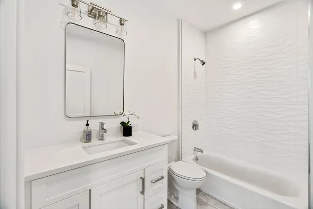 a bathroom with a toilet a sink a tub and mirror