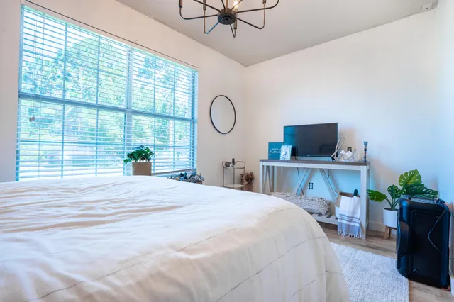 a bedroom with a bed a chandelier and a large window