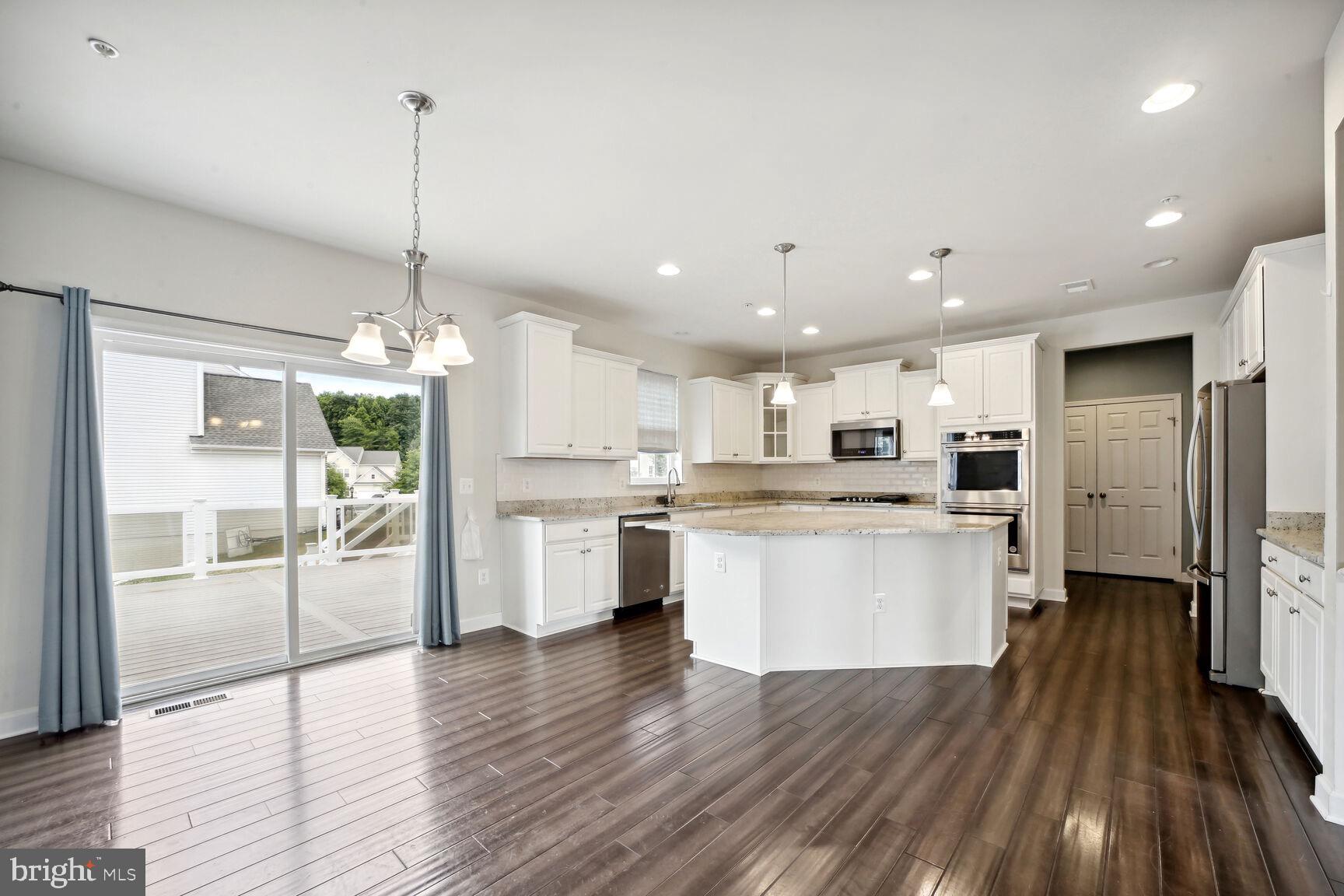 6201 Hunt Weber Drive Clinton, MD 20735 - Photo 9 of 30 a kitchen with stainless steel appliances kitchen island a refrigerator a stove a sink and a wooden floor