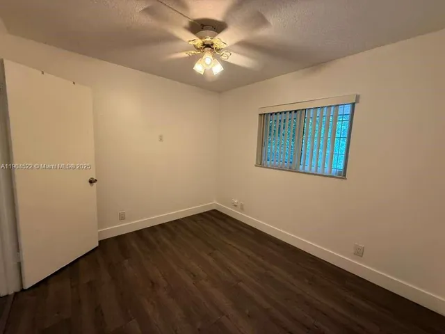 a view of an empty room with wooden floor and a ceiling fan